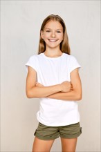 Portrait of positive teenager girl standing straight with crossed hands on chest