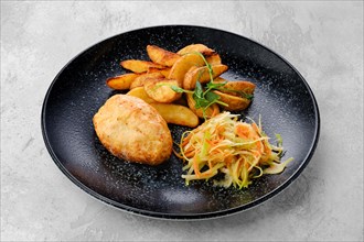 Kiev cutlet stuffed with cheese and butter served with fried potato wedges and pickled cabbage