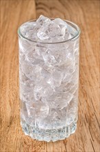 Glass of cold water with ice on wooden table