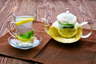 Antioxidant hot drink with lemon and mint in transparent tea pot and glass
