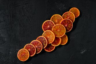 Overhead view of slices of blood orange on black background