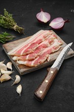 Slices of pork bacon on wooden cutting board