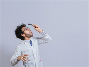 Surprised man in lab coat with magnifying glass looking at an advertisement above. Scientist man looking up with a magnifying glass. Amazed man observing an advertisement with a magnifying glass