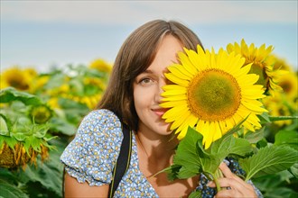 Joyful young woman hiding half of her face with sunflower