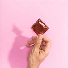 Close up man holding up red condom