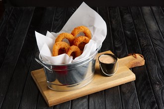 Snack for beer. Fried onion rings with sauce served in metal backet