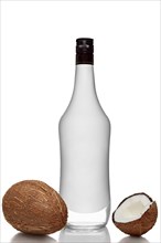 Bottle of alcohol beverage with coconut flavour with whole and opened coconuts with reflection on white background