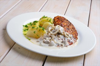 Fried chicken fillet in rosemary breading served with boiled potato and mushroom creamy sauce