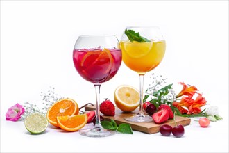 Two wine glasses with summer fruit and berry cocktails on white background