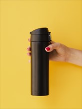 Hand holding thermos mock up yellow background