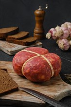 Smoked round beef sausage on cutting board over black background