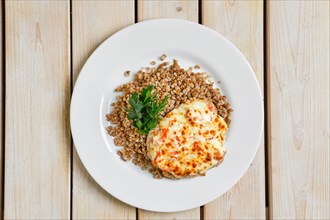Top view of chopped pork meat baked with cheese and tomato served with buckwheat porridge