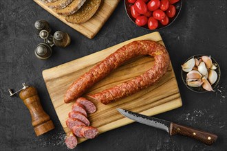 Overhead view of smoked beef sausage rings on wooden cutting board on kitchen table