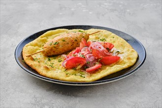 Kebab served on tortilla with tomato and red onion