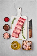 Raw fresh beef short rib stripes on wooden cutting board with spice and herbs for marinade