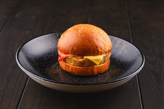 Simple burger with fish patty on wooden board