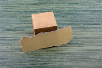 Torn paper and a paper box cube on wooden texture