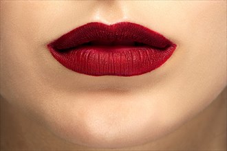 Close up photo of female face with tan makeup and red mat lips