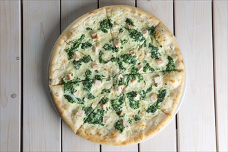 Top view of pizza with spinach and chicken on wooden table