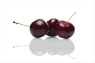 Three fresh cherries with reflection on glossy surface