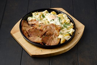 Fried pork t-bone chop with potato and egg on a plate