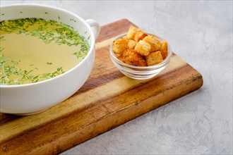 Closeup view of chicken stock with croutons on wooden serving board