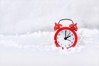 Winter time change for daylight saving in Europe on October 31st concept with red alarm clock between snow with copy space