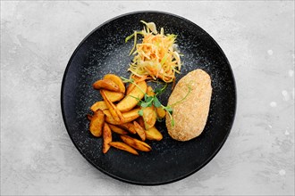 Cutlet stuffed with cheese served with fried potato wedges and sauerkraut