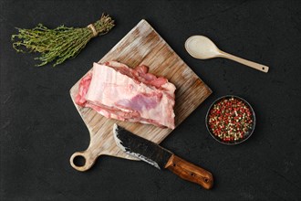 Overhead view of raw veal ribs with ingredients for cooking on black background