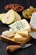 Assortment of cheese and snack for wine on dark wooden table