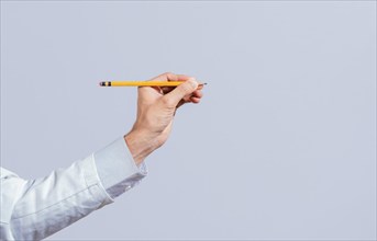 Male hand holding a pencil on a blank. Man fingers holding a pencil with blank space. Person hands holding a pencil on a space for text