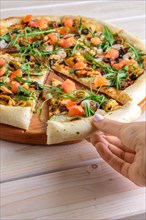 Hand picking slice of pizza with shrimps