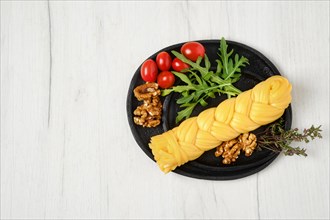 Smoked braided cheese with walnuts and tomatoes on a plate