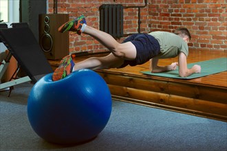 Athletic man doing balancing exercises with the gym ball. Fitness workout