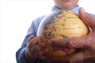 Baby with blue shirt holding a globe in hand on white background