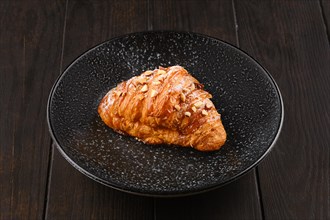Freshly baked big croissant with caramel on a plate