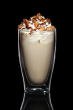 Double walled glass with coffee cocktail decorated with whipped cream and nuts isolated on black