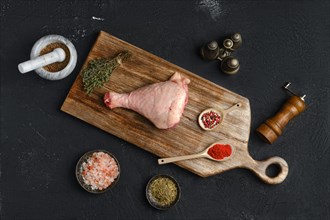 Raw turkey drumstick with skin on wooden board