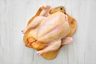Fresh raw whole farm chicken on wooden cutting board