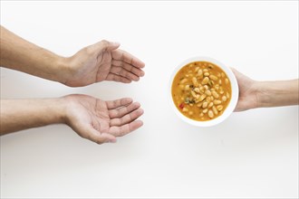 Hand giving soup bowl needy person