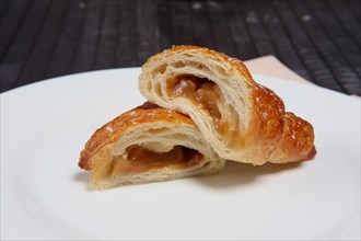 Fresh baked croissant on plate divided on pieces