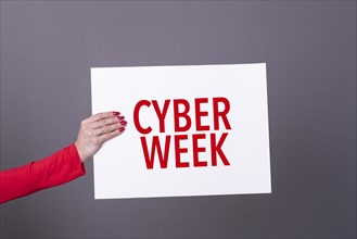 Female hand holding a cyber week poster. Studio shot. Commercial concept