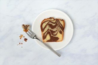 A piece of marble cake and fork on plate