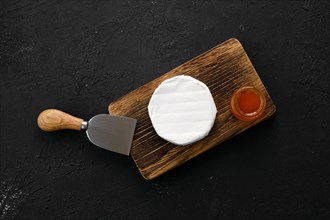 Piece of soft brie or camembert cheese on cutting board