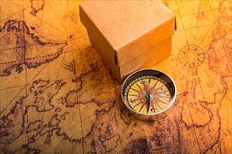 Compass on old map beside a box as a concept of traveling