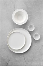 Overhead view of white tableware on grey background