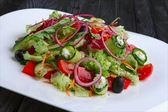 Salad with feta cheese rolled in cucumber slices with tomato and red onion
