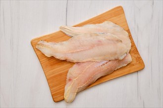 Top view of raw fresh haddock fillet on wooden cutting board