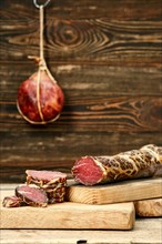 Smoked dried beef meat cut on slices on wooden cutting board