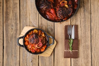 Overhead view of cast iron skillet with ossobuco on wooden table
